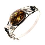 White metal hinged bangle of foliate design with large central amber-coloured cabochon, stamped 925