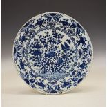 18th Century Delftware shallow dish, decorated with trees and rock work within floral borders,