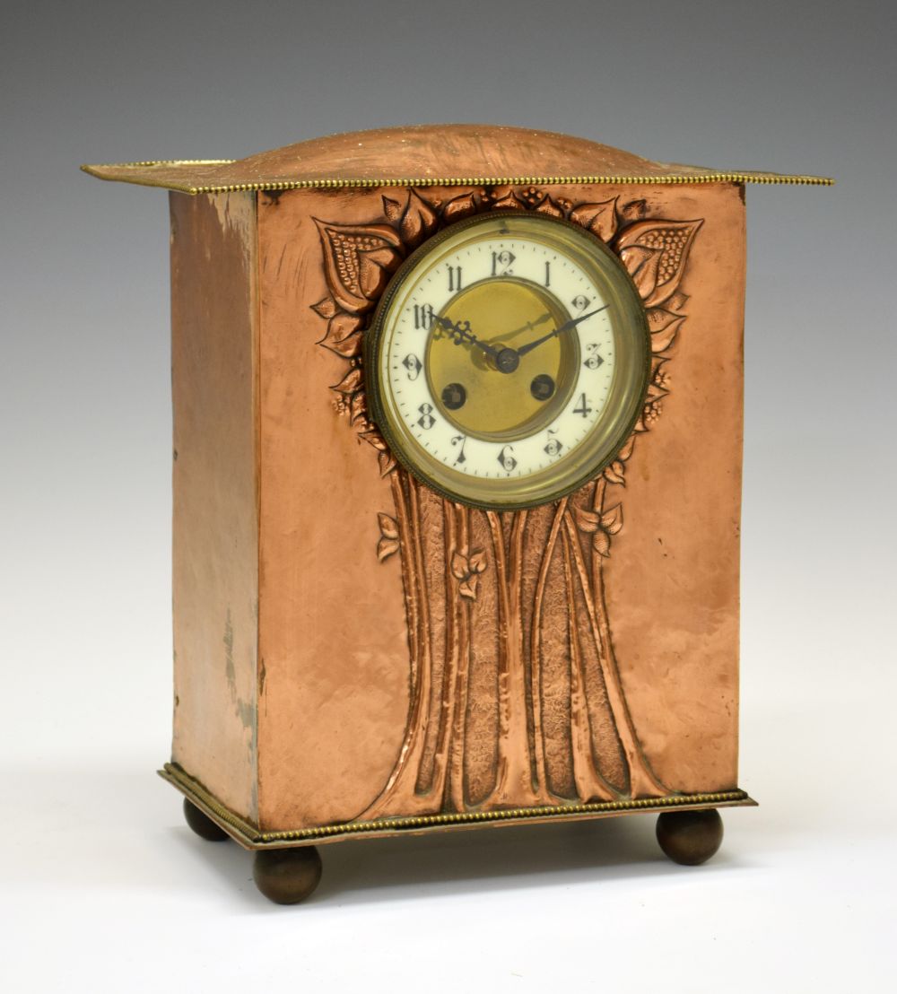 Arts & Crafts/Art Nouveau copper mantel clock, with humped overhanging roof above repousse flowering