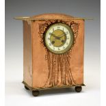 Arts & Crafts/Art Nouveau copper mantel clock, with humped overhanging roof above repousse flowering