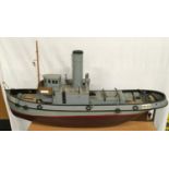 A hand built wooden model of a grey painted single funnel tug with internal motor. Approx 90cms.