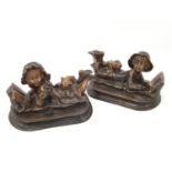 A pair of bronzed reclining statues of two children with their pets.