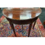 A Victorian mahogany demi lune fold over card table resting on tapered legs to castors. H:75 W:83.