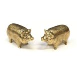 A pair of gold plated condiments in the form of pigs.