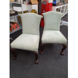 A pair of antique oak framed living chairs with carved legs depicting ladies heads.