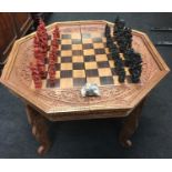 A carved wooden games table and playing pieces.