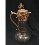 A Victorian glass claret jug with silver plated handle and lid. Lion statue and other decoration