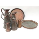 A collection of copper jugs and trays in embossed n the shape of snakeskin