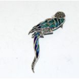 A silver and plique a jour parrot brooch with ruby eyes.