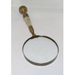 A large brass and mother of pearl handle magnifying glass.