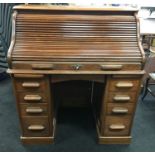 An oak roll top office desk with fitted interior and key.