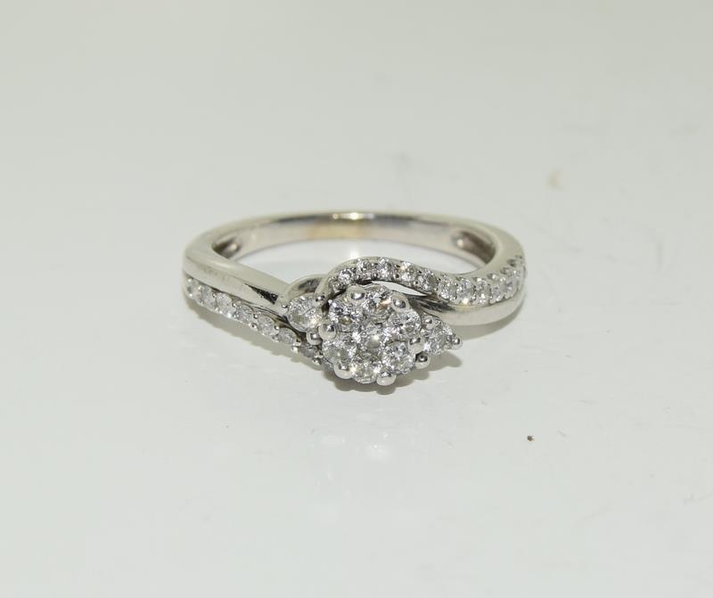 A Diamond cluster twist and diamond shoulder ring on white gold size L.