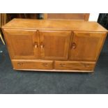 An Ercol golden blonde Windsor sideboard with three doors over two drawers.