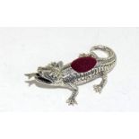 A silver alligator pin cushion