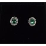 A pair of white gold emerald and diamond cluster earrings of 70 points.