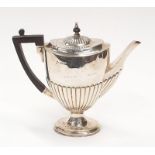 A solid silver tea pot with fluted design and Bakelite handle.