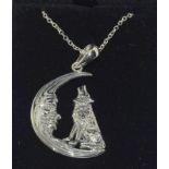 A silver pendant necklace of a dog howling at the moon.