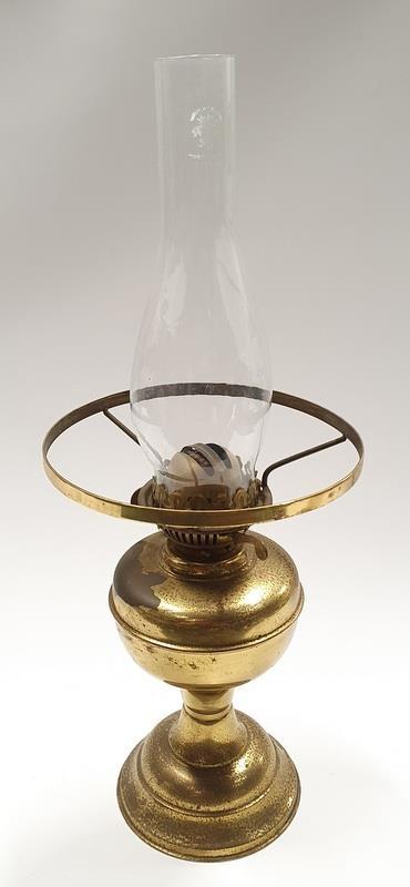 A brass oil lamp with glass chimney.