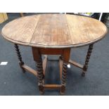 A vintage oak gate leg table with barley twist supports.