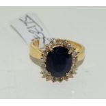 A Sapphire approx 3.0ct center surrounded by 18 diamonds approx 0.60ct in 18ct gold ring . Size N