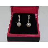 A pair of white gold diamond and cultured pearl drop earrings.