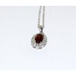 An 18ct white gold garnet and diamond pendant necklace.