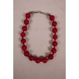 A red coral beaded necklace with a white metal clasp, 19" long