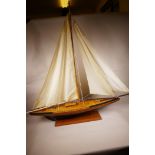 A scratch built wooden Bermuda rigged racing yacht with linen sails, 42" long, on a wooden display