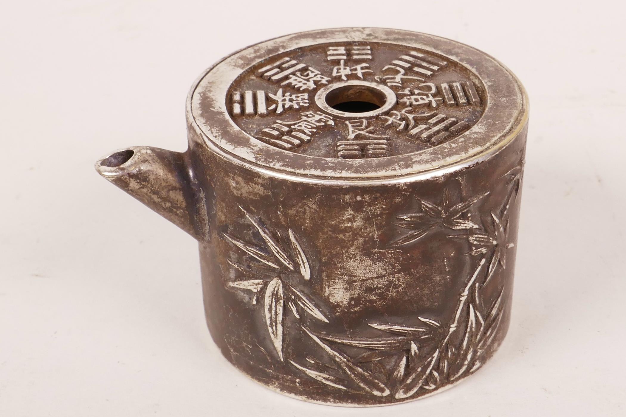 A small Chinese white metal pourer in the form of a teapot decorated with character marks and