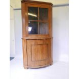 A Dutch blond walnut corner display cabinet, with glazed upper section and bowfront base, raised