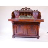 A William IV mahogany cylinder top desk, fitted with pigeon holes and drawers over pull out slide