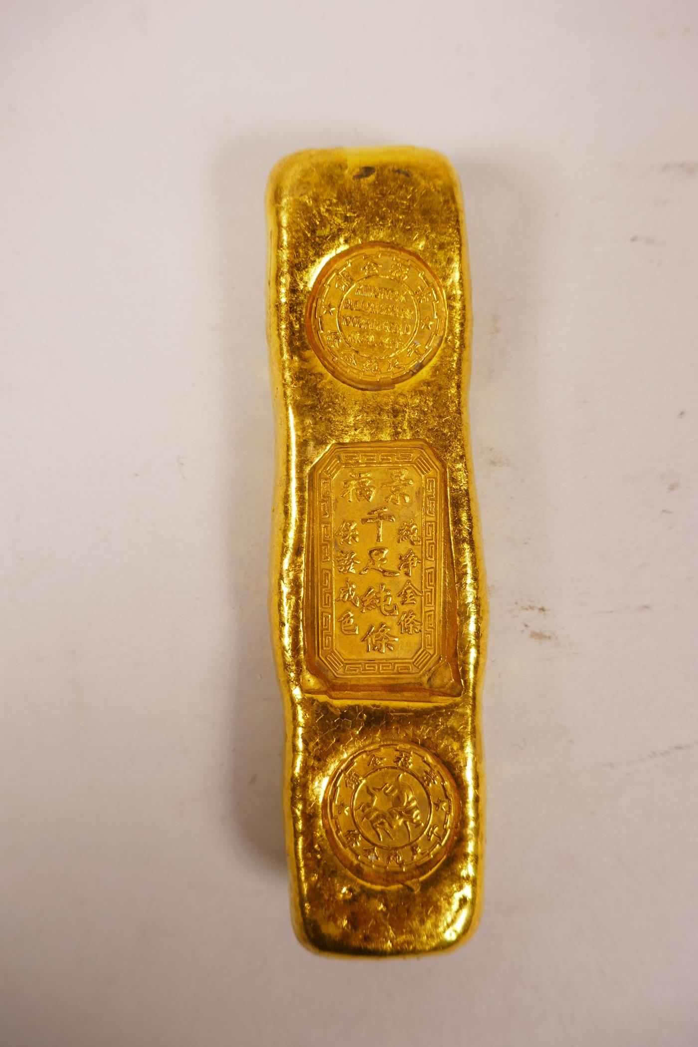 A Chinese gilt white metal trade token/ingot, 4" long, 190 grams