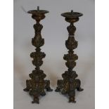 A pair of antique repoussé brass pricket candlesticks raised on scroll supports, 17" high