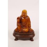 A Chinese soapstone carving of Lohan, on a hardwood stand, with a fitted hardwood box decorated with
