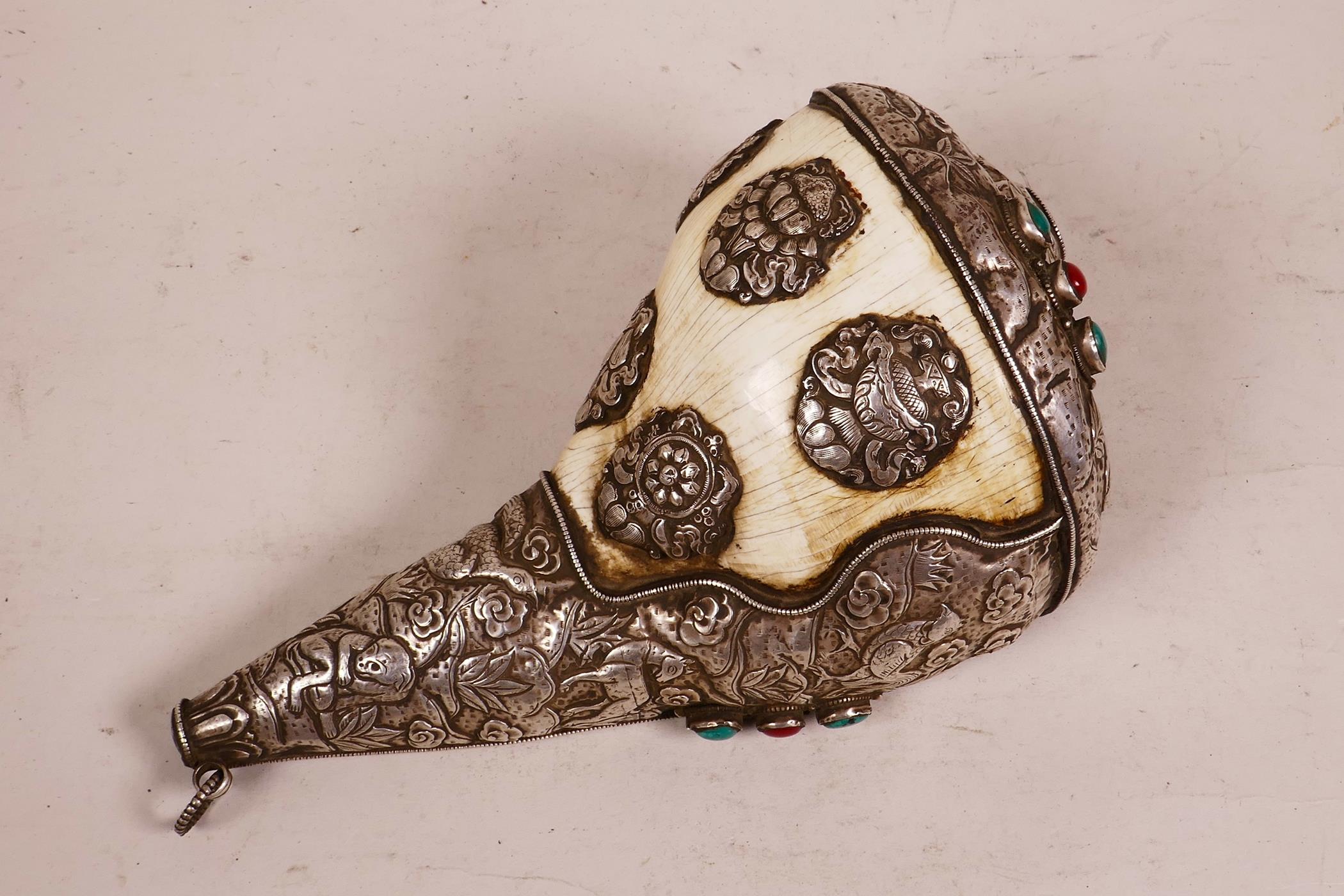 A large Tibetan white metal mounted conch shell, with repoussé decoration of the eight Buddhist