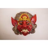 A Balinese carved and painted wood mask of a wrathful deity/spirit, 13" x 12½"