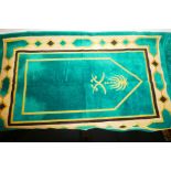 An Eastern prayer rug bearing the Saudi coat of arms on a green ground, 42" x 26"