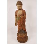 A painted wood figurine of Buddha standing on a lotus flower, 23" high