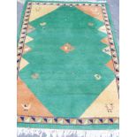 An Indian hand woven deep pile wool carpet with stylised bird decoration on a green field, 72" x 49"