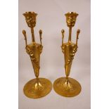 A pair of ormolu Empire style candlesticks decorated with swags and flowers, with Bacchus head