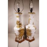A pair of Oriental porcelain table lamps decorated with gold coloured flowers on a white ground,