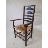 A C18th ash ladderback elbow chair with a rush seat, shaped arms and two front stretchers, good