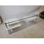 A mid C20th chrome framed coffee table with a glass top and four white melamine swing shelves, 51" x