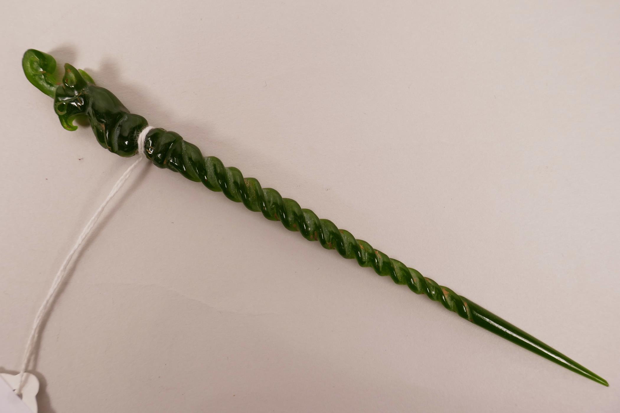 A Chinese green hardstone hair pin with a spiral stem and carved mythical creature to end, 7½" long