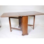 An Art Deco figured walnut drop leaf table with gate leg action, raised on a shaped base, 33" x