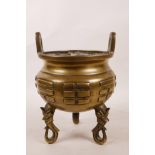 A Chinese brass two handled censer on tripod mask supports decorated with the 'Bagua' (the eight