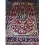 A red ground Persian Tabriz carpet with a traditional design and blue ground border, 118" x 80"