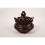 A Chinese ribbed bronze censer and cover on tripod supports with two handles, the cover decorated