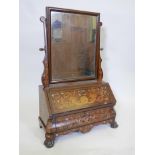 A C19th marquetry inlaid mahogany fall front toilet mirror, with shaped drawers, raised on ball