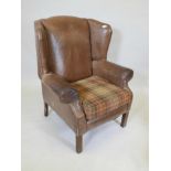 A brown leather wing armchair on reeded front supports